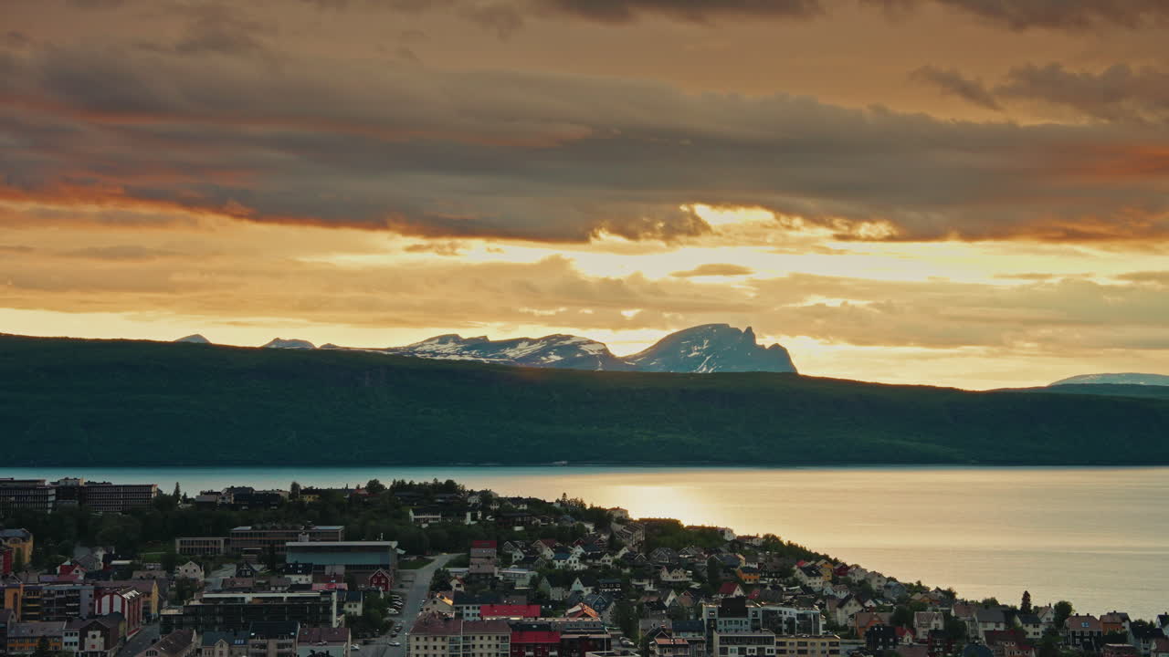 Midnight sunset over the nordic city of Narvik in Norway. View of the majestic fjords, the Norwegian sea and the cloudy, golden sky.
Picturesque arctic landscape.