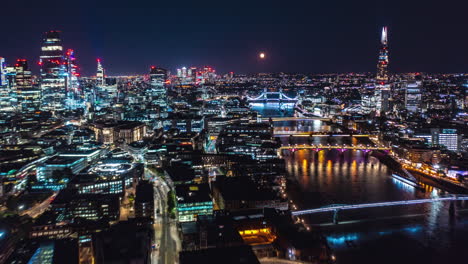 Fly-along-Thames-river-at-night.-Hyperlapse-of-cityscape-with-city-lights.-The-Shard,-skyscrapers-in-City-financial-hub-and-Tower-Bridge.--London,-UK