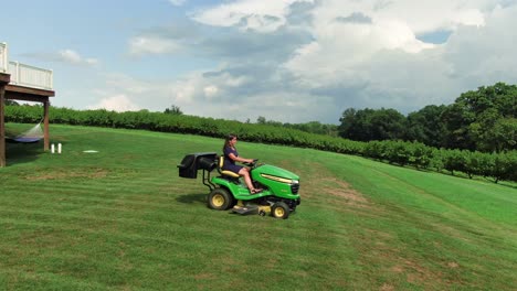 young hispanic woman mowing lawn on tractor cutter