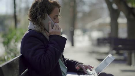 curly businesswoman talking on smartphone outdoor