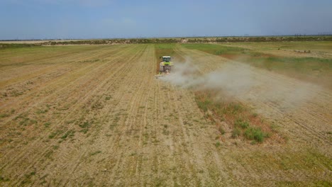 Aerial-View-Of-Tractor-Mowing-Grass-On-The-Field-At-Daytime-In-Almaty,-Kazakhstan---drone-shot