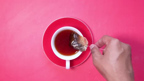 person removing tea bag from cup of tea.