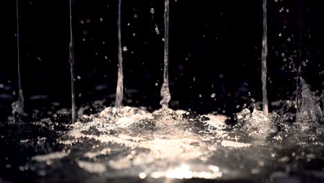 salpicaduras de agua con luz por la noche de cerca