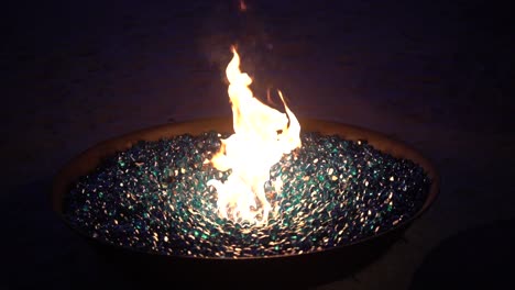 leuchtende blaue glasfelsen in einer gasfeuerstelle im freien.