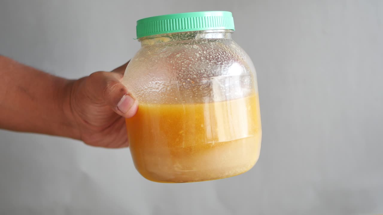 Hand Holding a Jar of Ghee or Honey