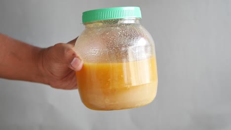 hand holding a jar of ghee or honey