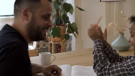 Padre-Feliz-Ayudando-A-Su-Hijo-Con-La-Tarea-En-Casa