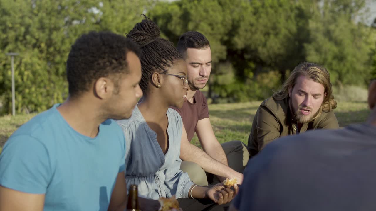 Side view of cheerful friends having picnic in park