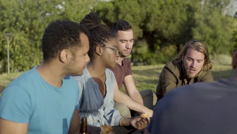 side view of cheerful friends having picnic in park