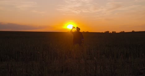 Betrunkener-Bauer,-Der-Bei-Sonnenuntergang-Alkohol-Auf-Dem-Feld-Trinkt