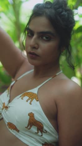 confident young woman posing outdoors in printed top, tropical natural light