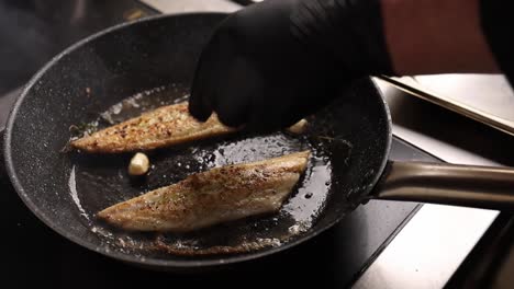 chef cooking fish in a pan