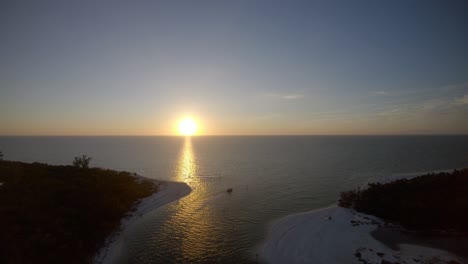 Imágenes-Aéreas-De-Drones-De-4k-De-La-Puesta-De-Sol-Y-Reflejándose-Sobre-El-Mar-En-Un-Paso-Tranquilo,-En-Nápoles,-Florida,-EE.UU.