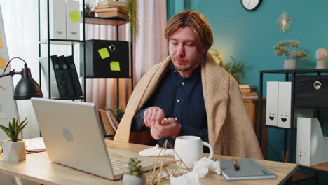 sick ill young businessman suffering from cold flu or allergy wipes snot working on laptop at office
