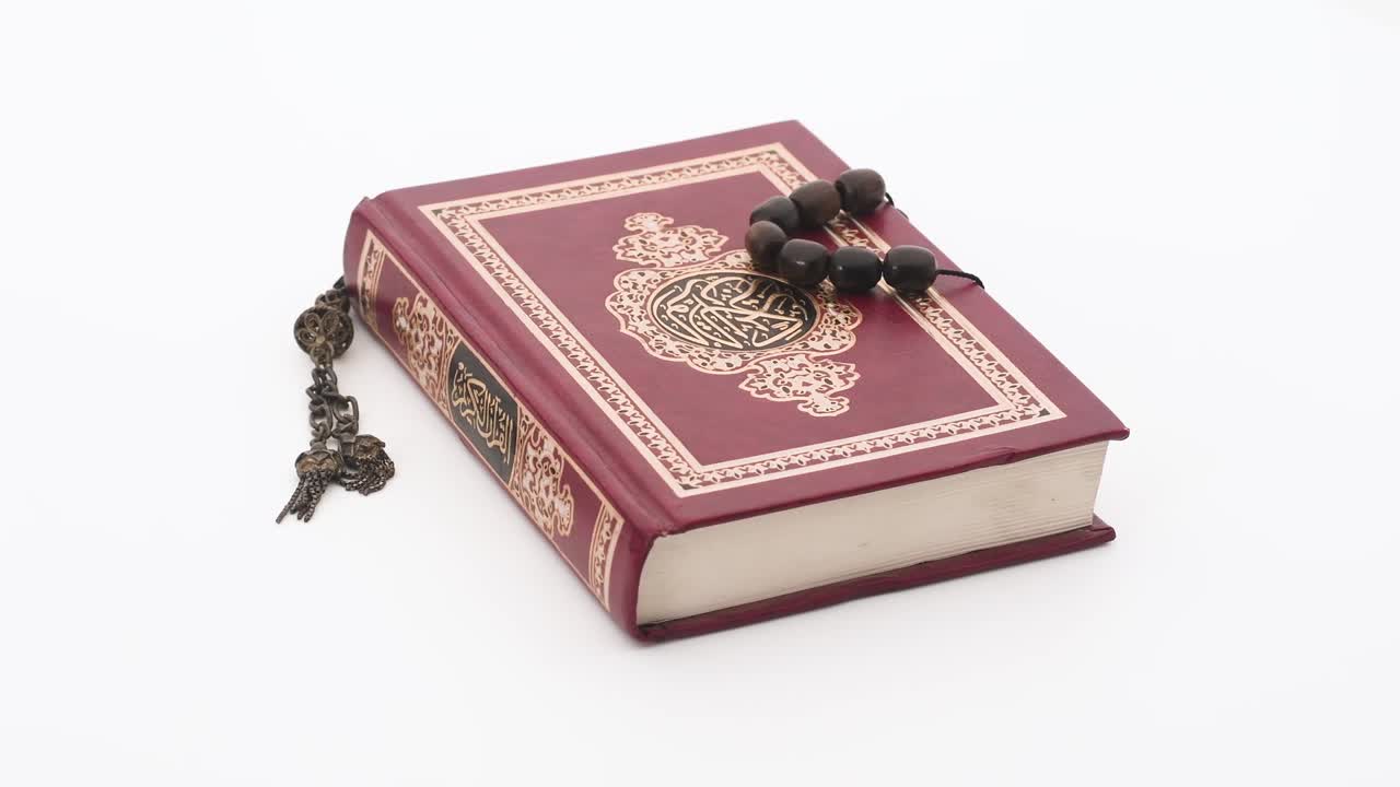 libro sagrado islámico de 4k con rosario en un fondo blanco giratorio, la traducción es el corán kareem en árabe