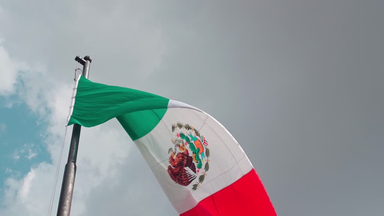 Mexican flag on a pole waving gently in the wind. Slow motion