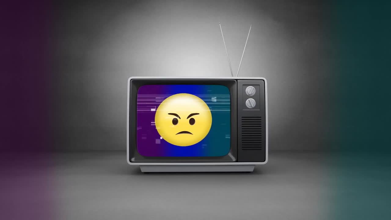Retro television with angry emoji on sizzling screen. TV is on the floor on grey room