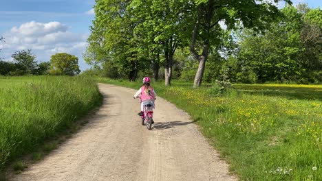 一位年輕女孩騎著她的單車穿過草原的塵土飛揚的道路上