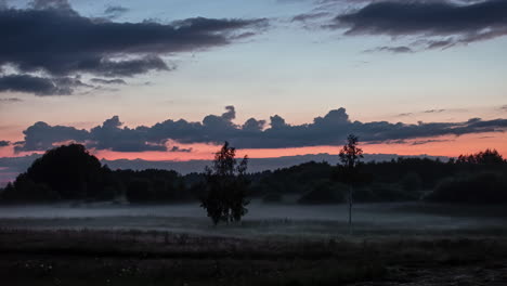 view of green landscape with mist, fog and rain dark clouds moving in timelapse footage in the evening