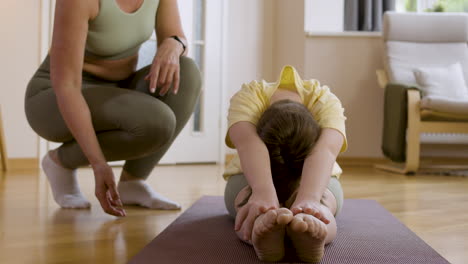 woman helping girl with flexibility at home