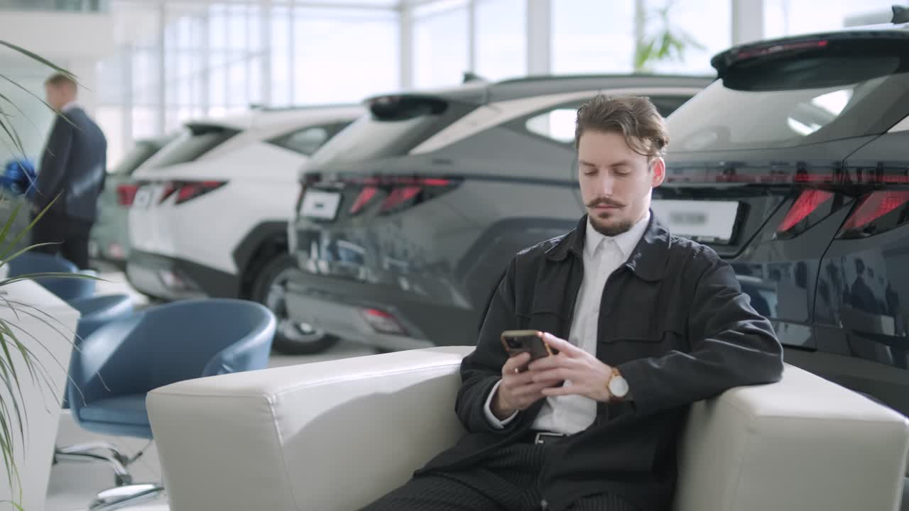 A man using his smartphone in a car dealership