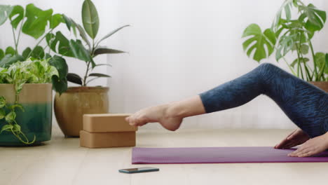 atractiva mujer de yoga ejerciendo un estilo de vida saludable practicando una pose de flexión sentada hacia adelante disfrutando del entrenamiento en casa entrenando en una colchoneta de ejercicios