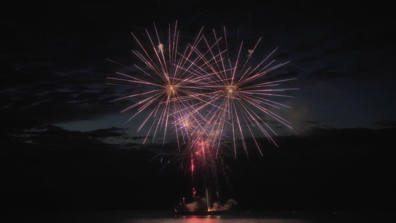 Scatto astratto di fuochi d'artificio che esplodono sopra il lago di notte. Lunga esposizione.