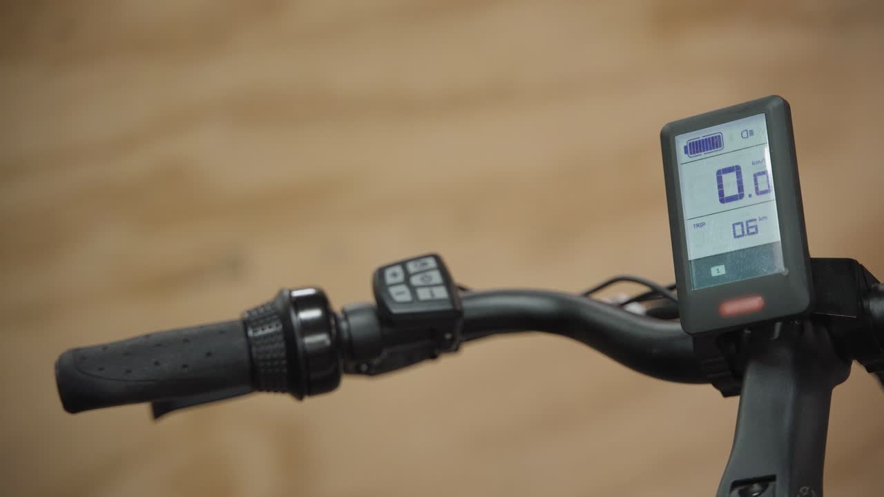 primer plano de un hombre que enciende la alimentación con los botones en el manillar de una bicicleta eléctrica y la pantalla led se enciende
