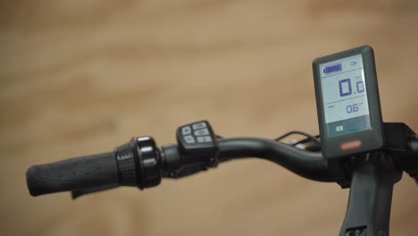 close up of a man turning the power on with the buttons on the handle bar of a electric bike and the led display screen turns on