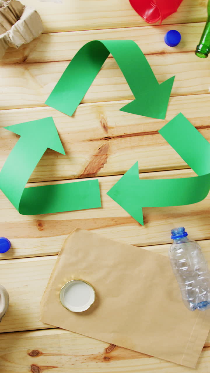 Vertical video of trash and recycling symbol of green arrows with copy space on wooden background