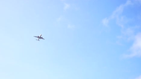 Close-up-low-shot-of-an-airplane-soaring-through-a-cloud-dotted-sky-on-a-clear-day