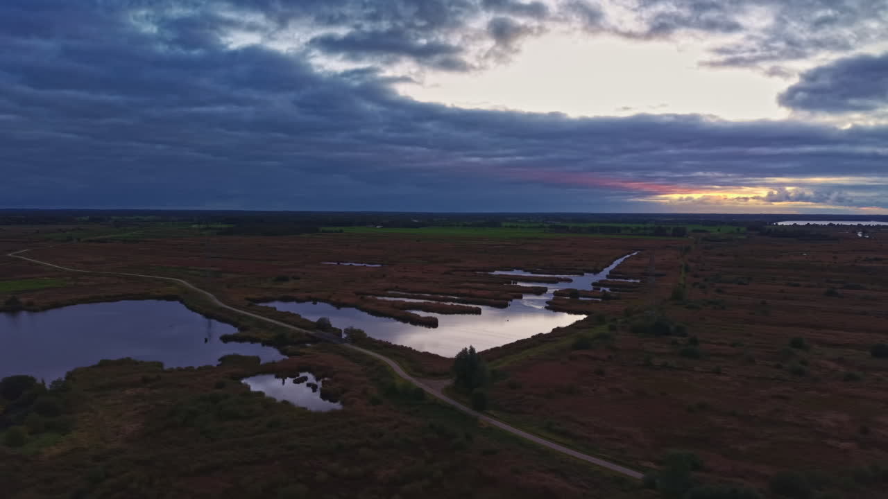 Solnedgang over rolige marskområder med fredfyldt vand, der afspejler en farverig himmel i aftenlyset i skumringen