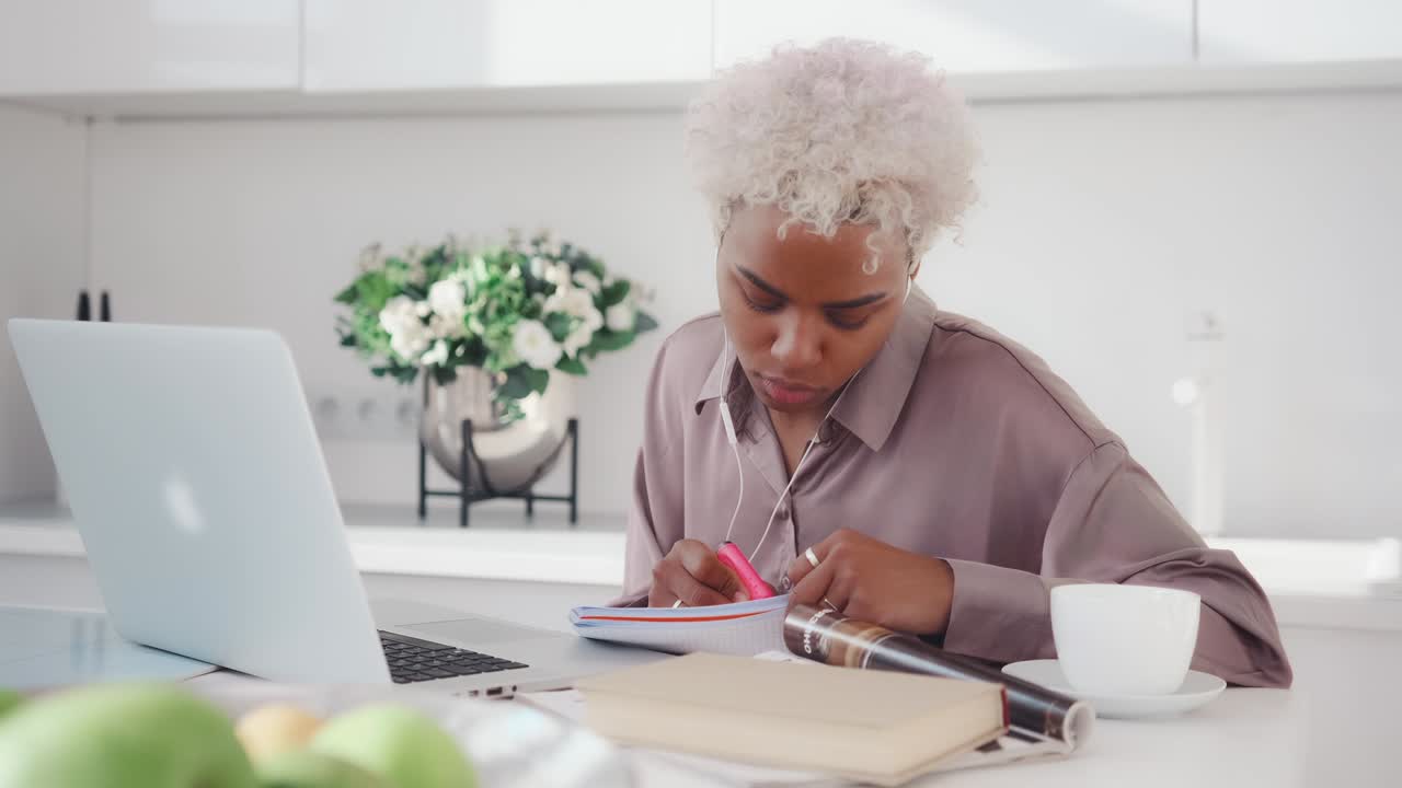 Giovane donna d'affari afroamericana che guarda il laptop e prende appunti