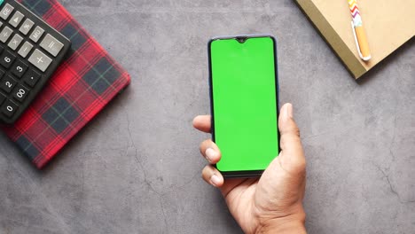 top view of man hand using smart phone on office desk