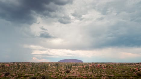 nubes de tormenta y lluvia pasando sobre uluru durante la puesta de sol