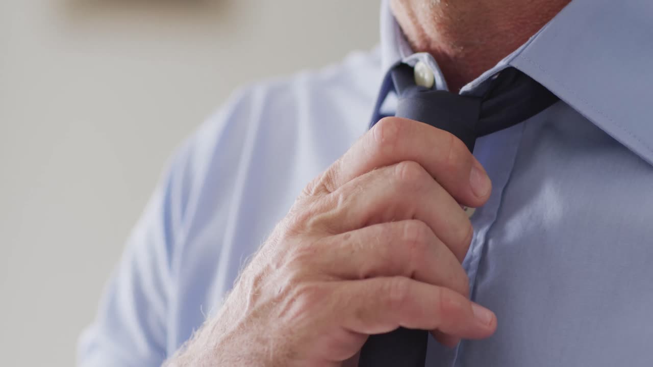 un hombre caucásico feliz de pie en la sala de estar y con corbata.