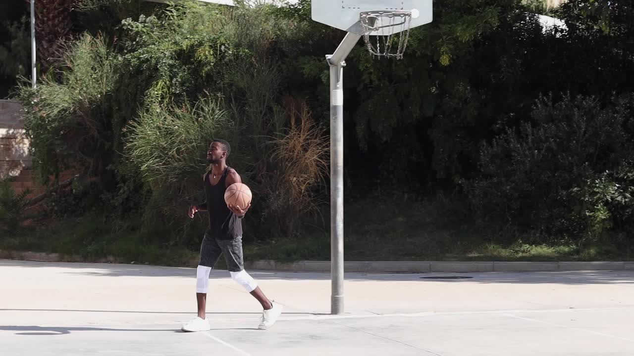 hombre negro jugando al baloncesto en el campo deportivo