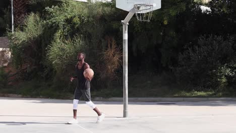 black man playing basketball on sports ground