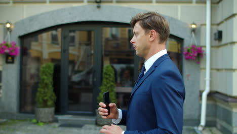 thoughtful businessman typing message on mobile phone outdoors.