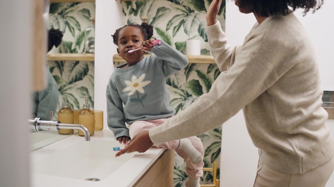 Young Girl and Mother Brushing Teeth in a Modern Bathroom