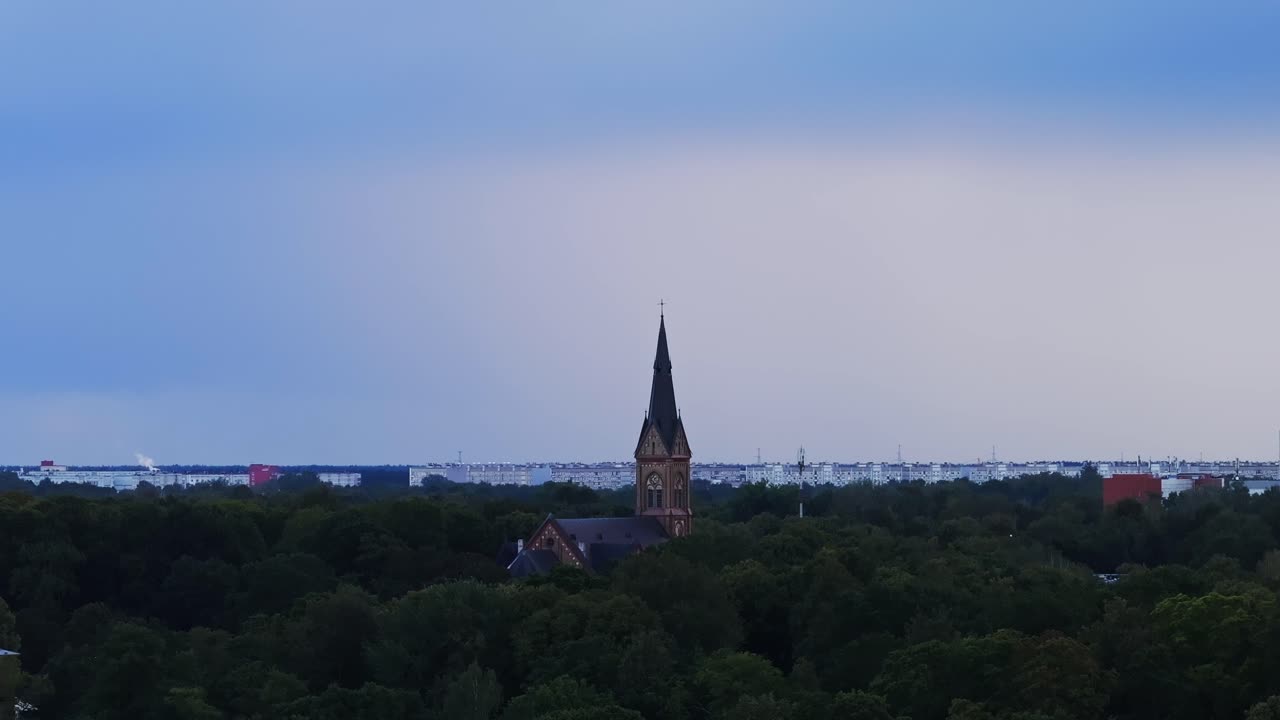 Drone orbiting Riga church as dark rain clouds move across evening sky