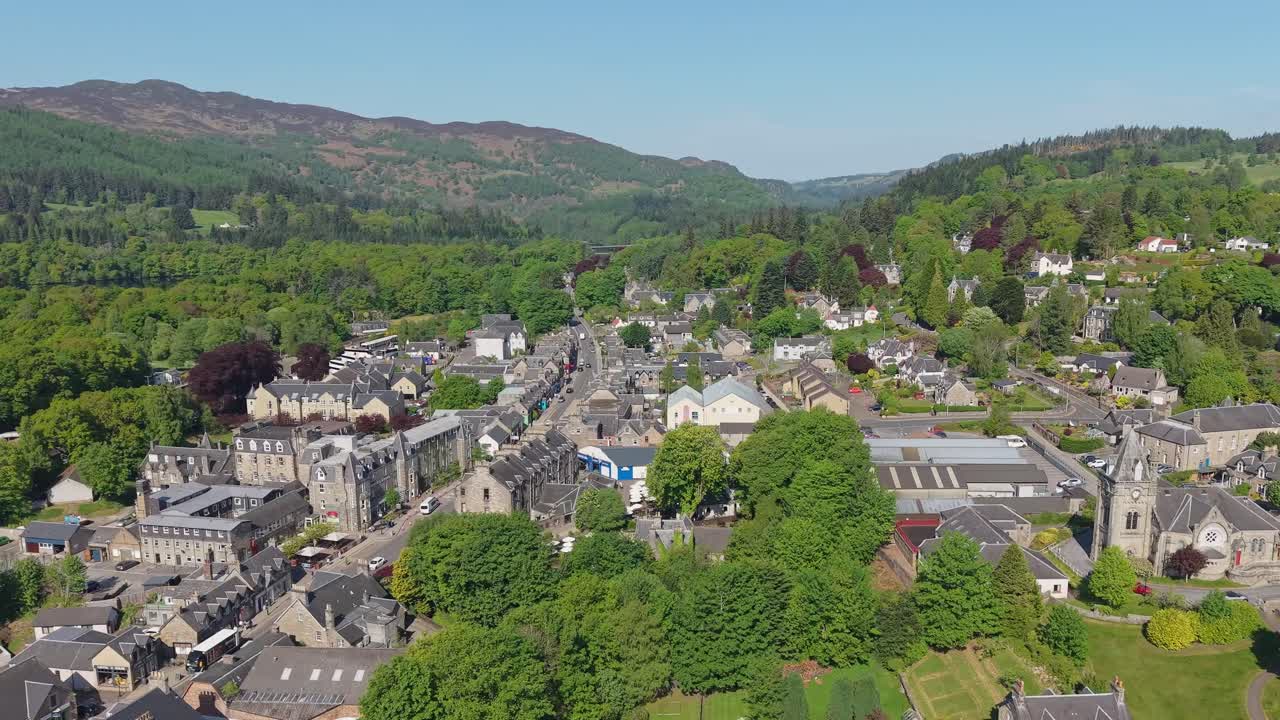 Parallel drone movement revealing Pitlochry village and the surrounding lush nature, showcasing charming streets and hills