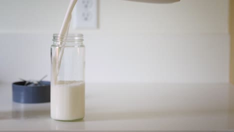 Filling-a-glass-jar-with-homemade,-sustainable-almond-milk