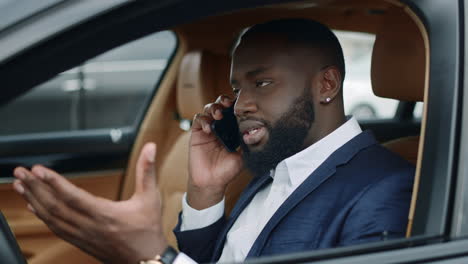 hombre afro en primer plano hablando por teléfono en el coche. hombre sentado en el asiento delantero en un coche de lujo