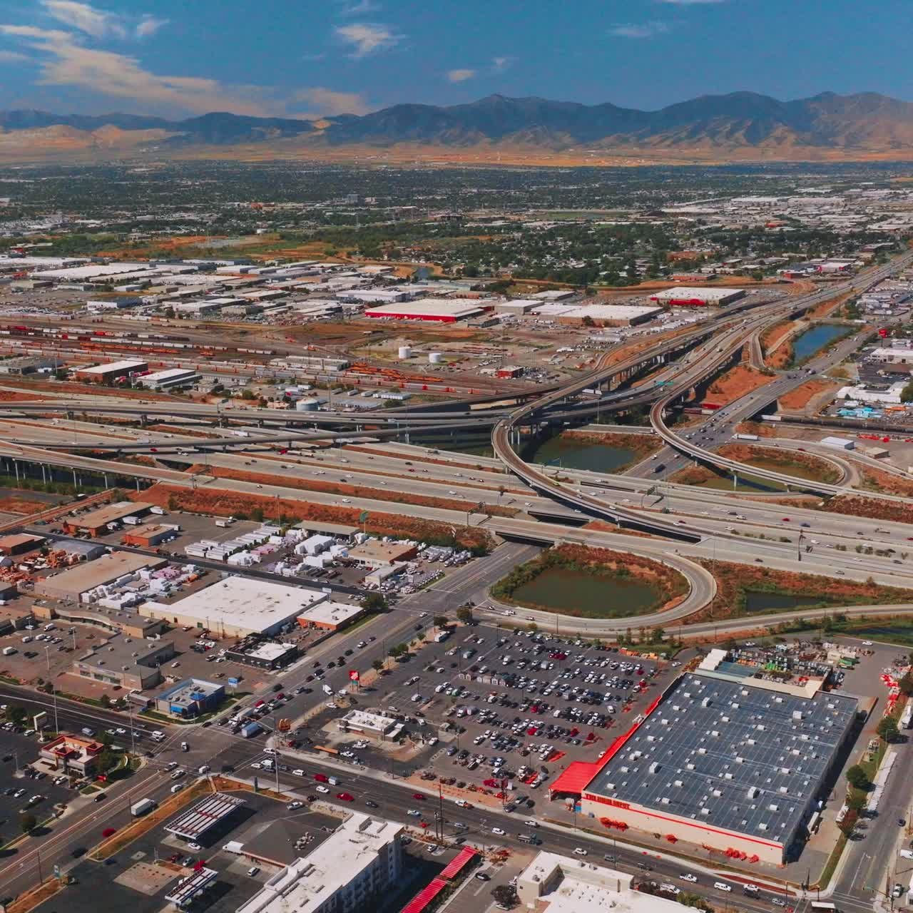 Big parking lots and complicated roads at the outskirts of Salt Lake City. Mountains of Utah at backdrop. Top view