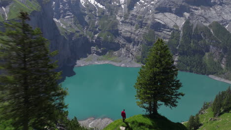 tourist hiking on steep ridge overlooking oeschinen lake in kandersteg, switzerland