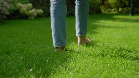 female feet walking barefoot on grass in manicured lawn, low angle