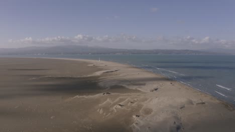 alta y amplia vista aérea del faro del delta del ebro en la distancia con amplias dunas de arena de un lugar turístico popular en españa
