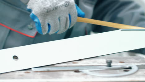 worker of metalworking workshop measuring metal billet with tape measure