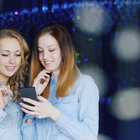 two young women use a smartphone and have a good time 2